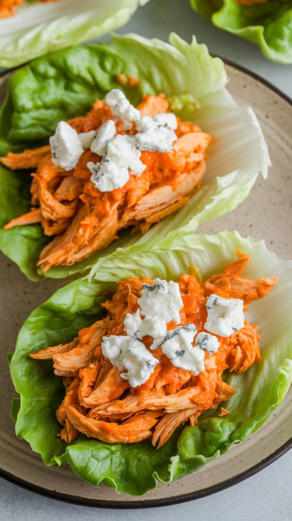 Buffalo Chicken Lettuce Wraps with shredded chicken and blue cheese on lettuce leaves