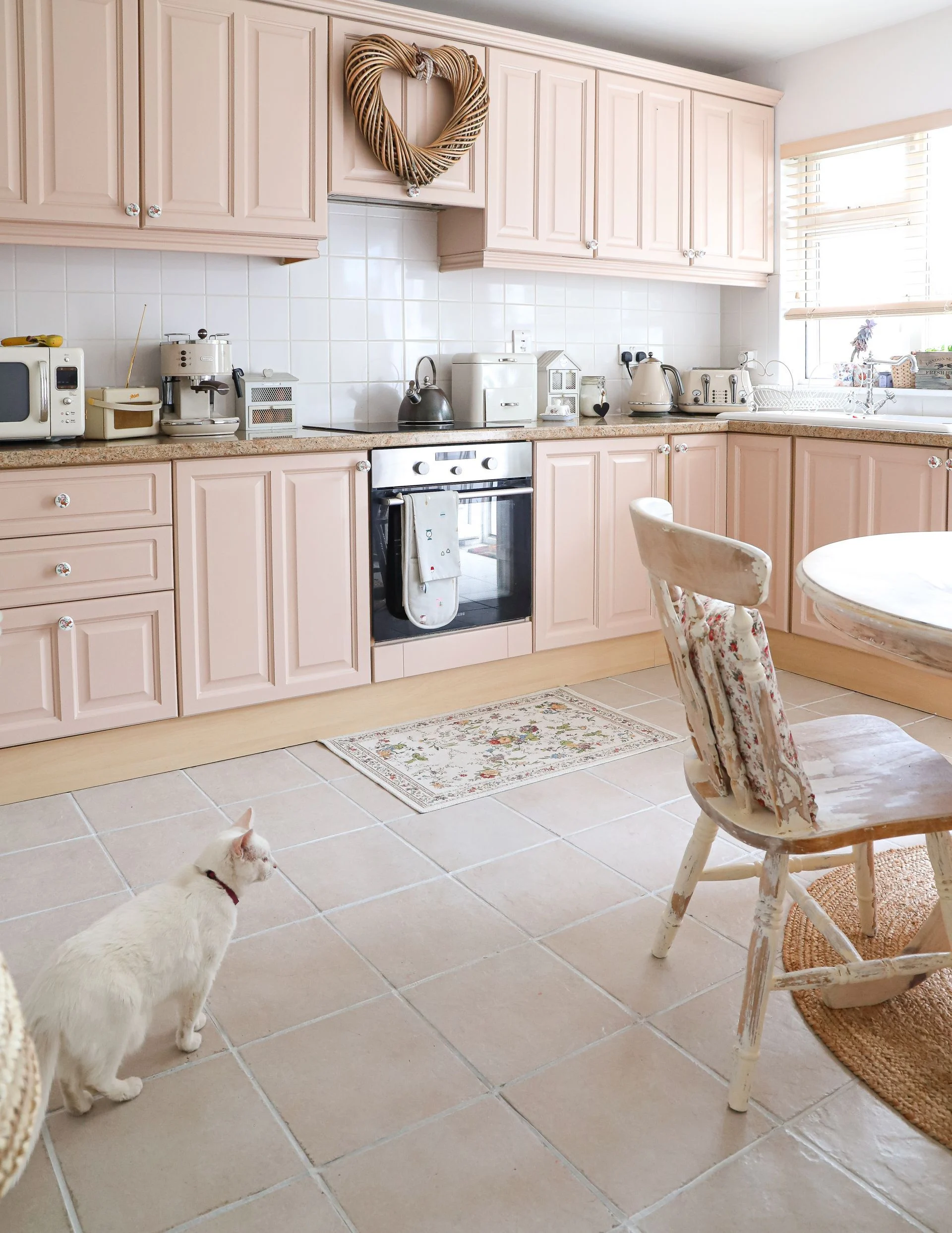 Hand painted pink shaker kitchen with granite counters and floral knobs