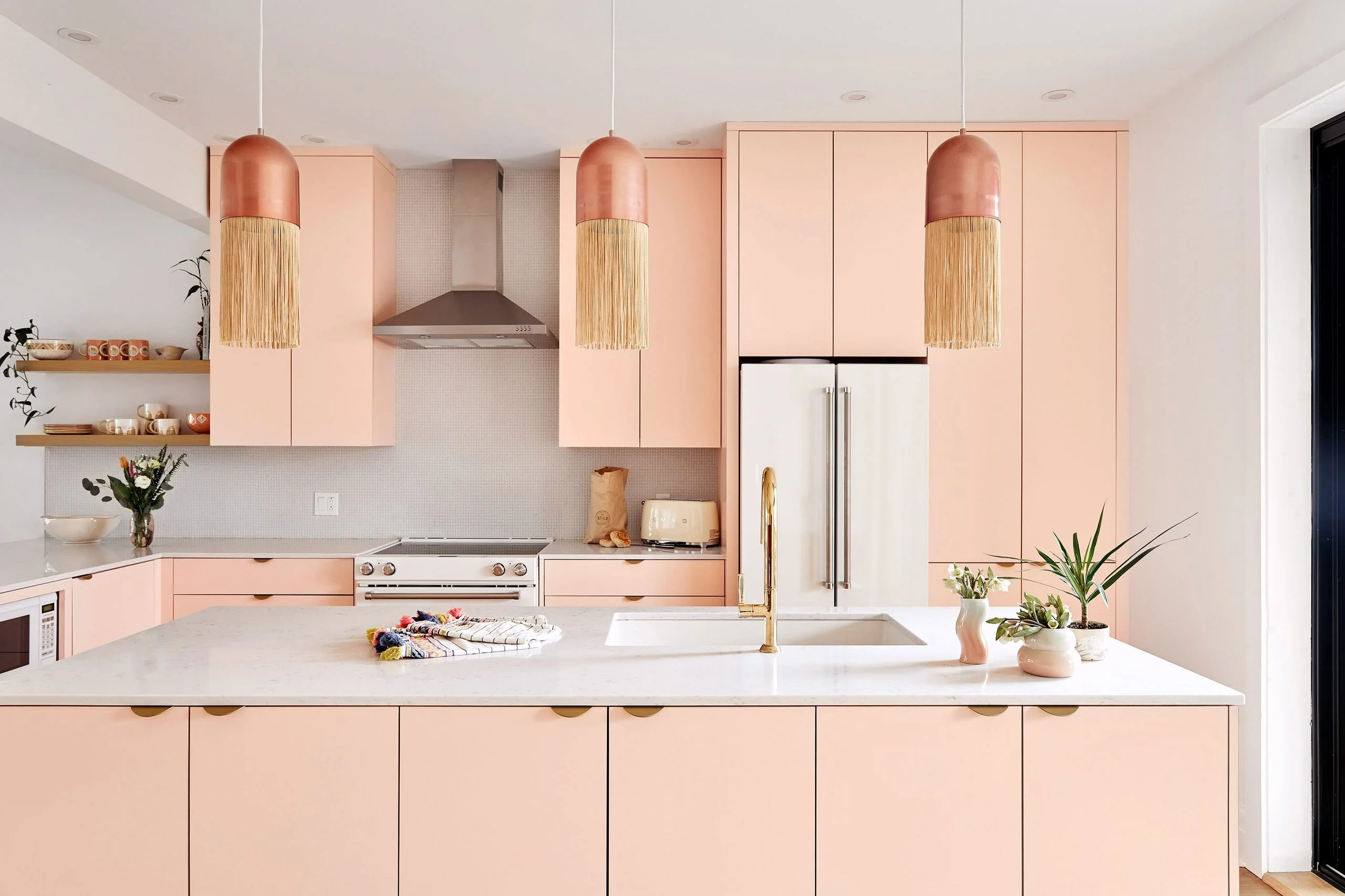 Modern peach pink kitchen with large island and copper fringe pendant lights